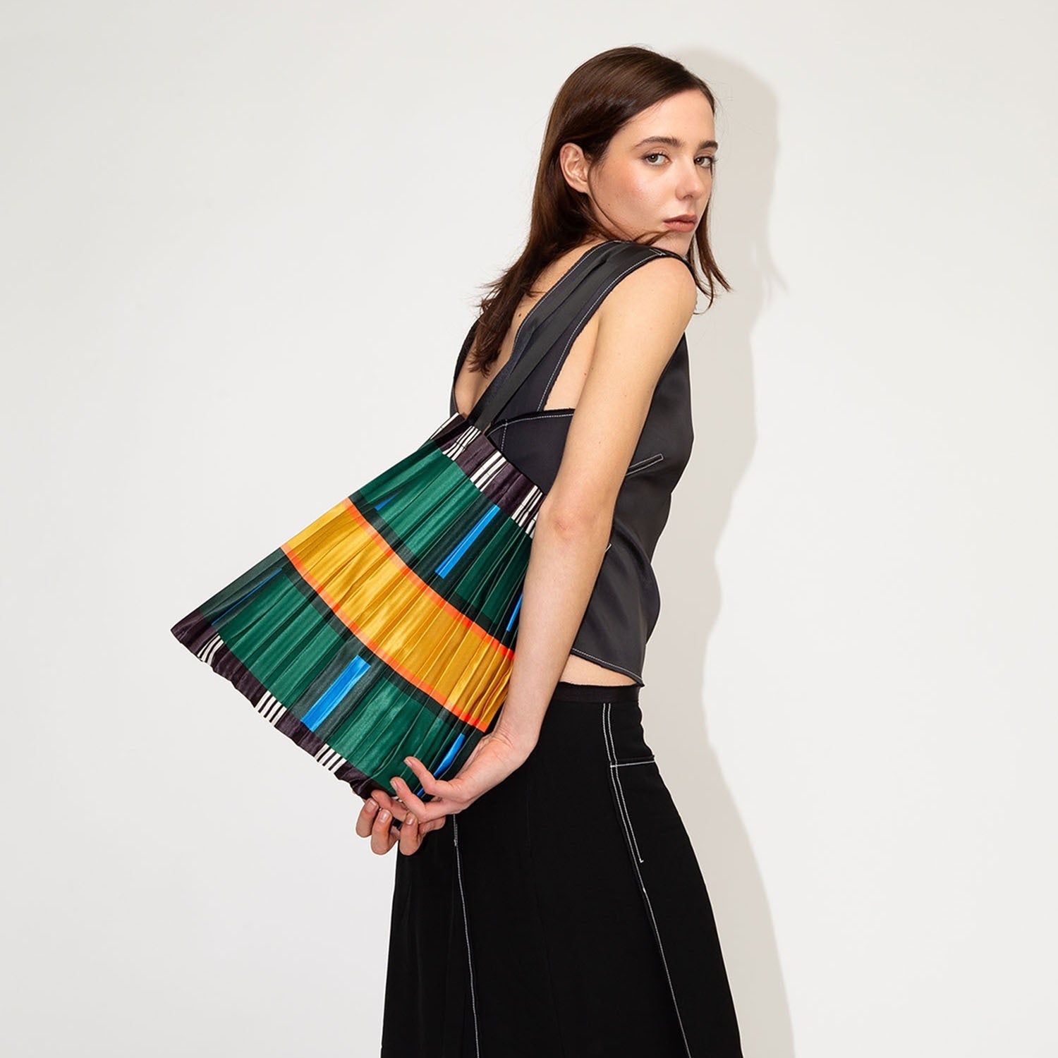 Woman holding a colorful striped bag against a white background