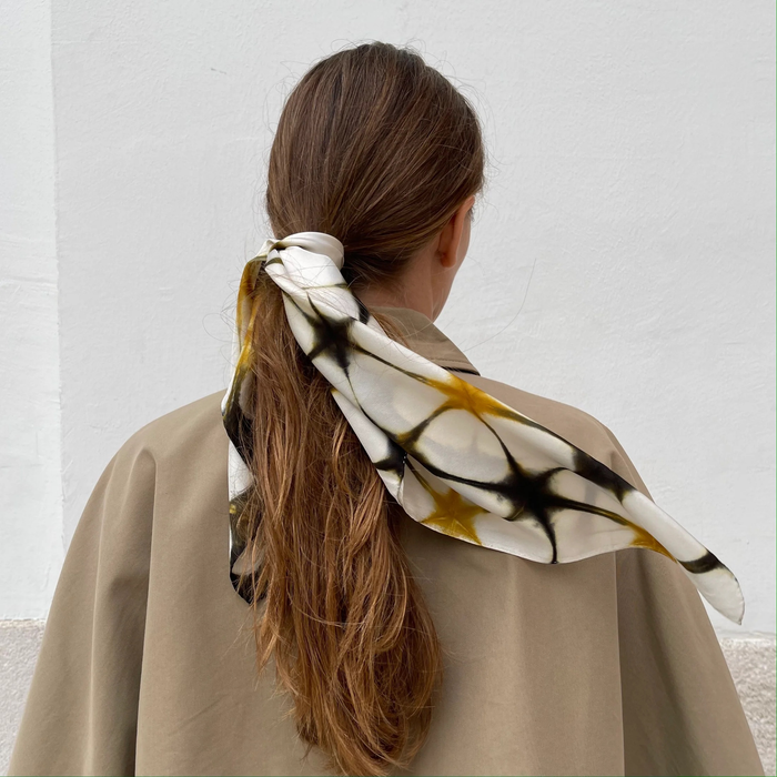 Silk scarf on manequin blowing in breeze. Scarf is coffee, dark brown and white colours. Large blocks of colour. 