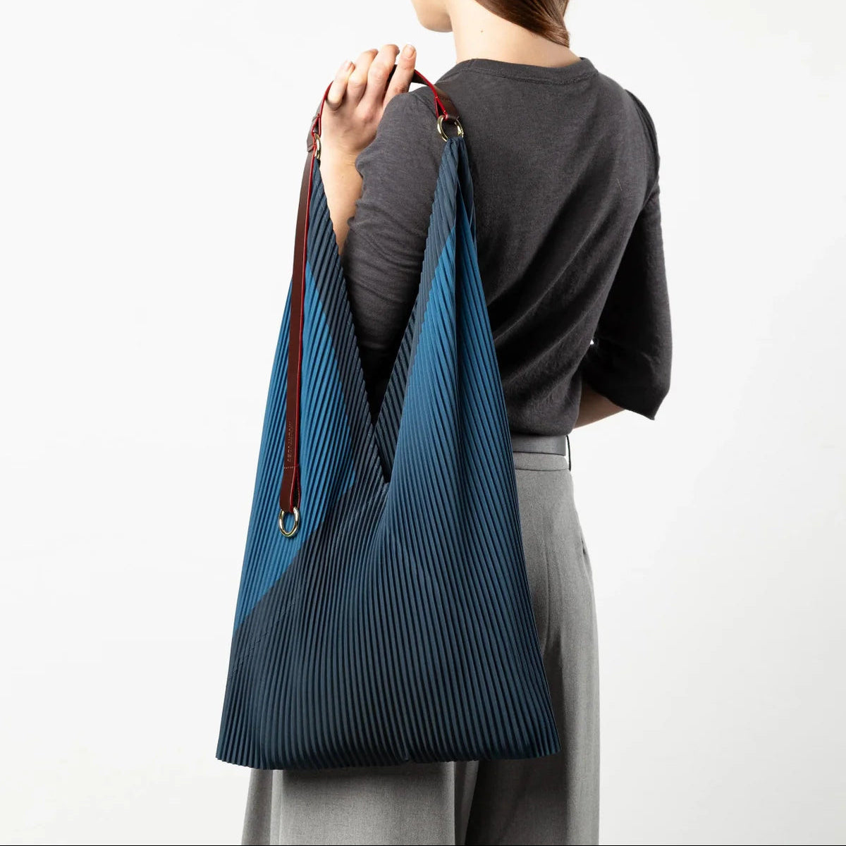 Person carrying a blue pleated bag on a white background