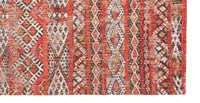 Corner closeup of rug with Morrocan nomad pattern in red tones.
