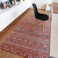 Rug with Morrocan nomad pattern in red tones on floor under desk.