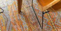 Detail view of rug with Morrocan nomad pattern in orange tones.