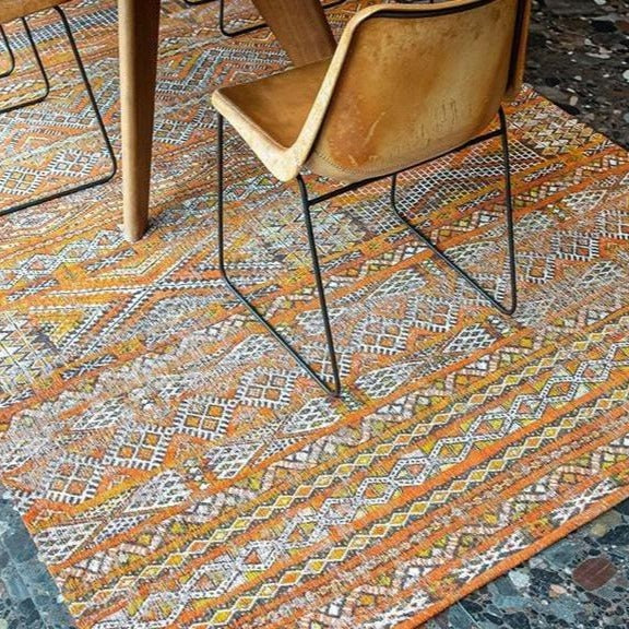 Rug with Morrocan nomad pattern in orange tones on floor of livingroom