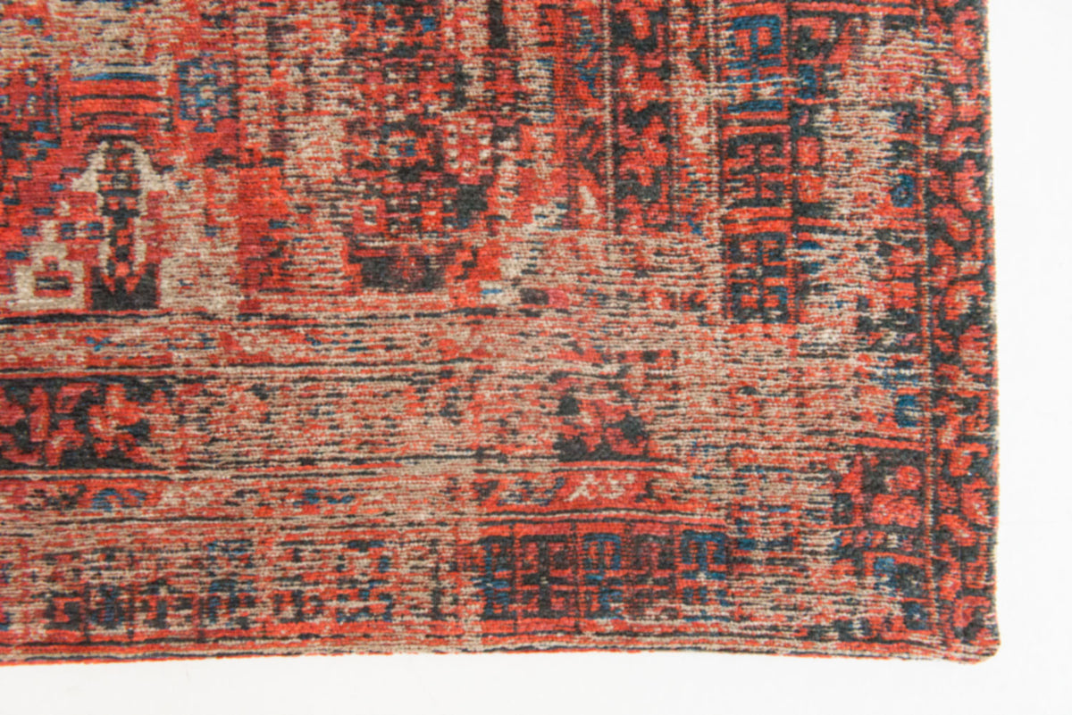 Edge detail view of rich red tone distressed rug with antique pattern detail