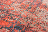Closeup of detail on rich red tone distressed rug with antique pattern