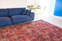 Livingroom view of rich red tone distressed rug with antique pattern detail