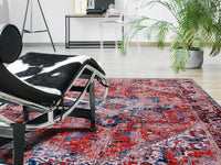 faded rug in red tones with blue detail in livingroom on white floor