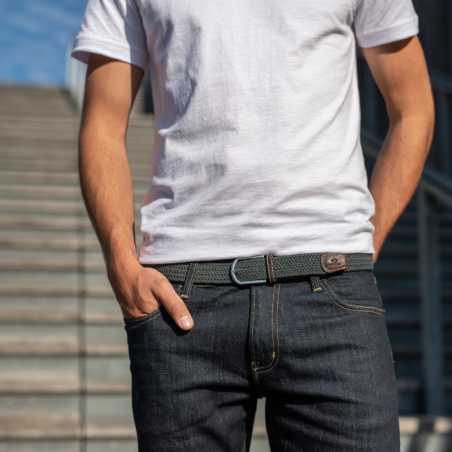 Elastic braided belt in dark grey, with brown leather finish on model against grey background in dark denim and white top