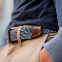 Blue and white Braided Belt with brown leather finish on model in beige pants and blue jersey